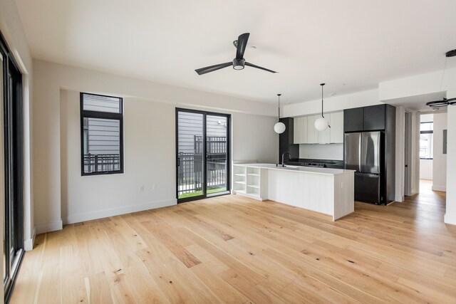 kitchen with pendant lighting, ceiling fan, stainless steel fridge, and light hardwood / wood-style flooring