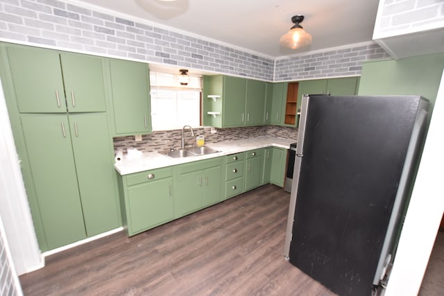 kitchen with sink, green cabinetry, appliances with stainless steel finishes, dark hardwood / wood-style floors, and backsplash