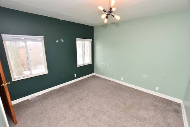 empty room with carpet and a notable chandelier