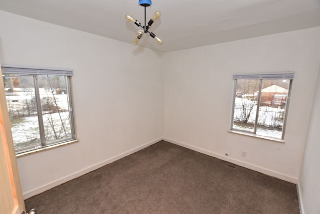 unfurnished room with dark carpet and plenty of natural light