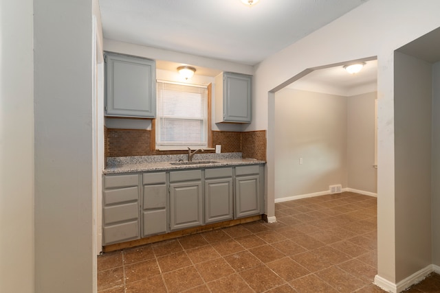 kitchen featuring tasteful backsplash, sink, and gray cabinetry