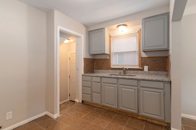 kitchen with tasteful backsplash, gray cabinets, and sink