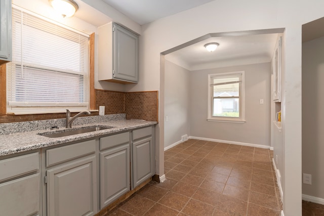 kitchen featuring gray cabinetry, sink, and decorative backsplash