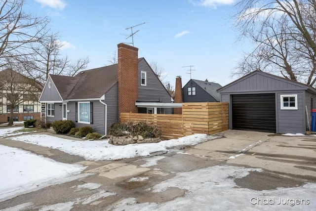 snow covered property with a garage and an outdoor structure