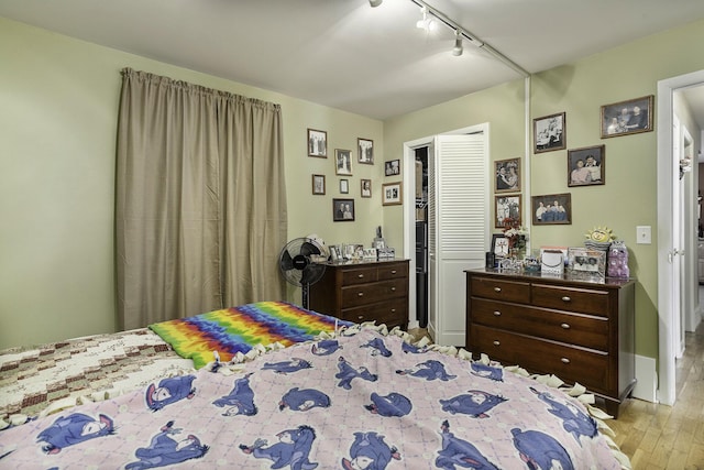 bedroom featuring rail lighting, light hardwood / wood-style floors, and a closet