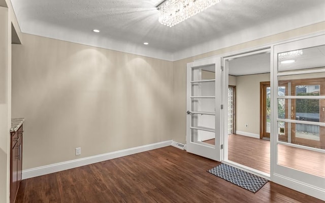 unfurnished room featuring dark hardwood / wood-style floors, a textured ceiling, and a notable chandelier