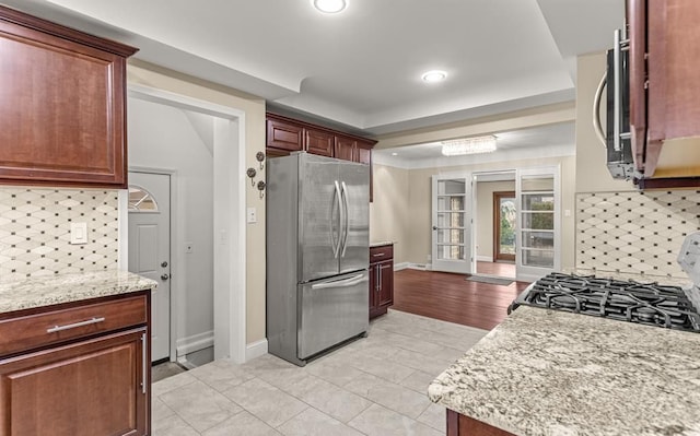 kitchen with light stone counters, stainless steel appliances, decorative backsplash, and light tile patterned floors