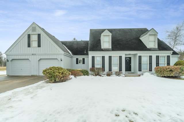 cape cod house with driveway, a shingled roof, board and batten siding, and an attached garage