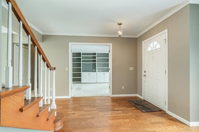 foyer with light wood-type flooring, baseboards, stairway, and crown molding