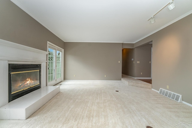 unfurnished living room with visible vents, baseboards, ornamental molding, a glass covered fireplace, and rail lighting