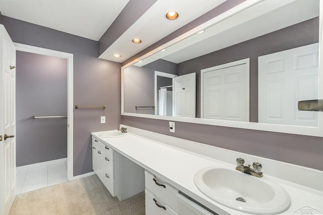 full bathroom with double vanity, tile patterned floors, a sink, and baseboards