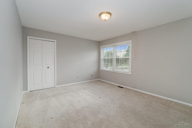 unfurnished bedroom featuring a closet, baseboards, visible vents, and carpet flooring