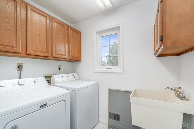 clothes washing area with independent washer and dryer, cabinet space, and a sink