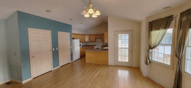 kitchen with hanging light fixtures, vaulted ceiling, white appliances, and light hardwood / wood-style flooring