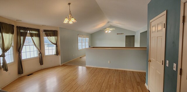 unfurnished room featuring ceiling fan with notable chandelier, lofted ceiling, and light hardwood / wood-style floors