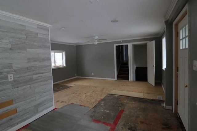 unfurnished room with ceiling fan, stairs, baseboards, and crown molding