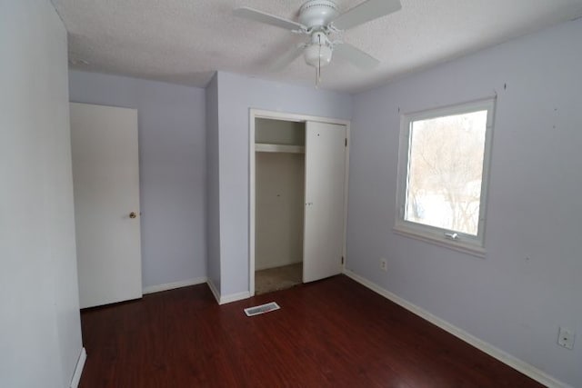 unfurnished bedroom with visible vents, dark wood finished floors, a textured ceiling, and baseboards