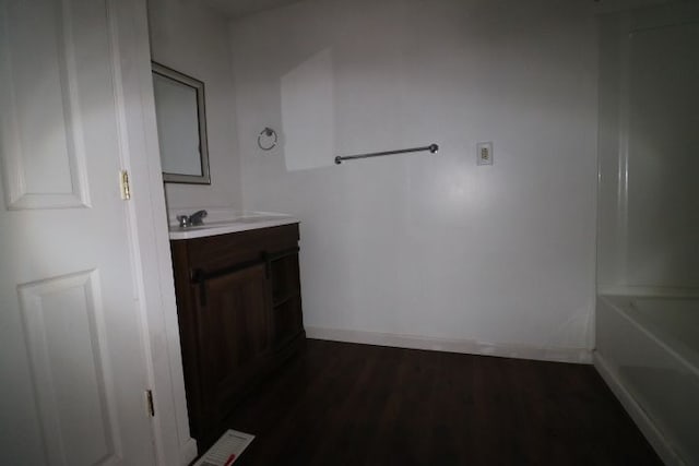 full bathroom with a bath, wood finished floors, vanity, and baseboards