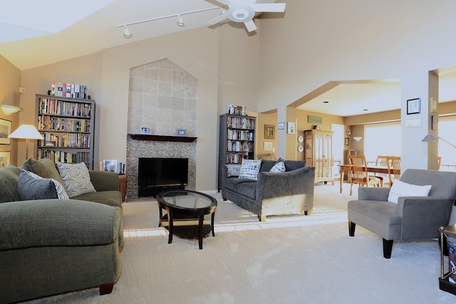 living room with light colored carpet, high vaulted ceiling, track lighting, ceiling fan, and a fireplace