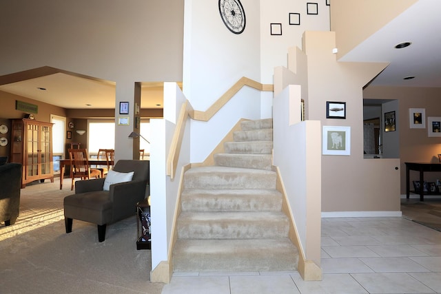 stairway with a towering ceiling and tile patterned flooring