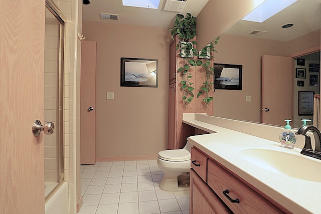 full bathroom with combined bath / shower with glass door, a skylight, vanity, tile patterned floors, and toilet