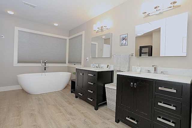 bathroom with a tub to relax in, wood-type flooring, and vanity