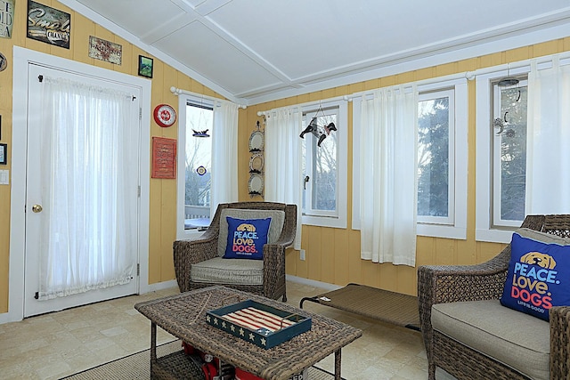 living area featuring plenty of natural light, wooden walls, and vaulted ceiling