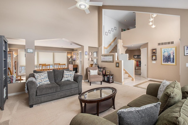 carpeted living room with ceiling fan and a towering ceiling