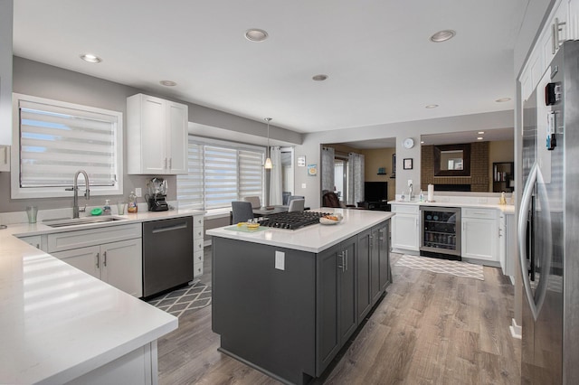 kitchen with a kitchen island, sink, white cabinets, wine cooler, and stainless steel appliances