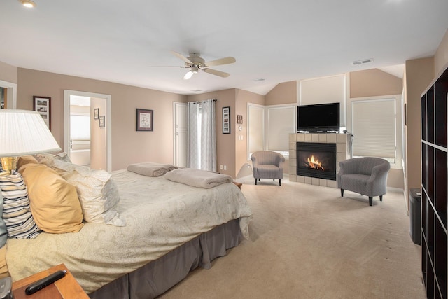 bedroom featuring lofted ceiling, a fireplace, light colored carpet, and ceiling fan