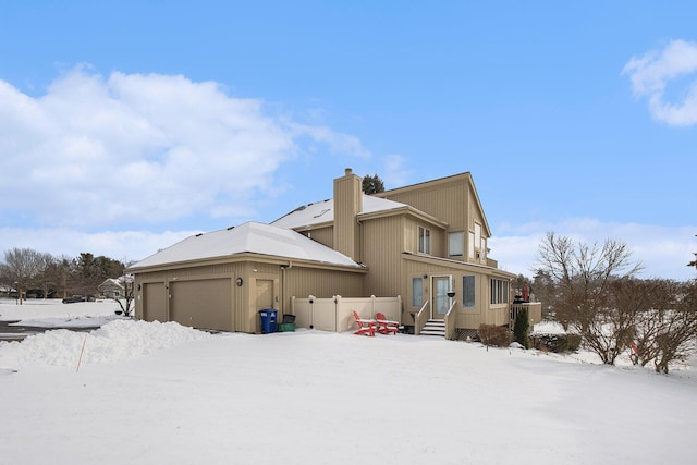 snow covered house featuring a garage