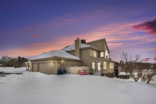 snow covered house featuring a garage