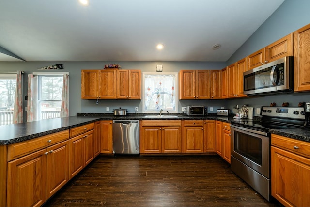 kitchen featuring vaulted ceiling, sink, kitchen peninsula, stainless steel appliances, and dark wood-type flooring