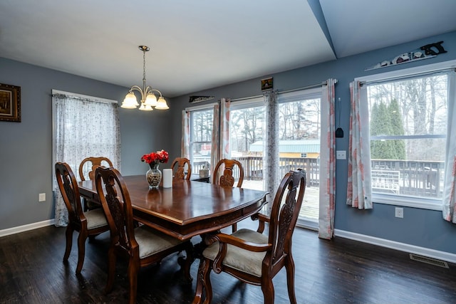 dining area with dark wood-type flooring, an inviting chandelier, and a wealth of natural light