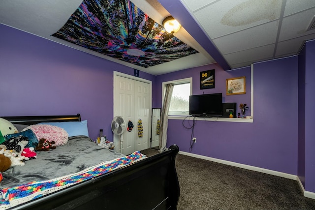 bedroom with a paneled ceiling, carpet flooring, and a closet