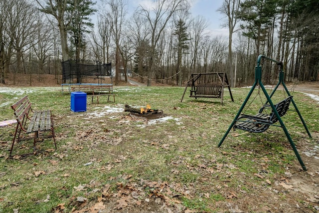 view of yard featuring a trampoline and a fire pit