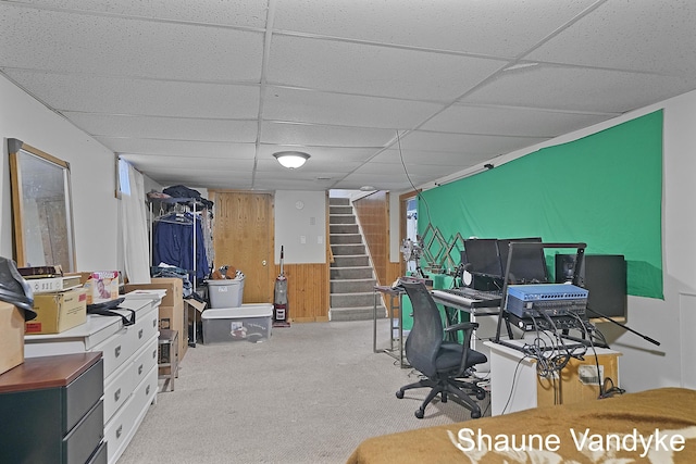 carpeted office featuring a paneled ceiling and wooden walls