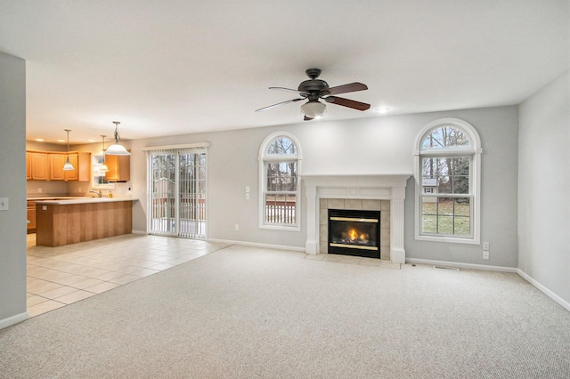 unfurnished living room featuring a fireplace, a wealth of natural light, light colored carpet, and ceiling fan