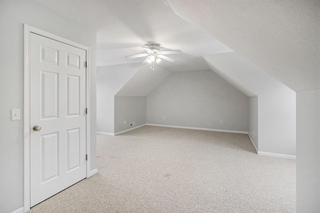 additional living space with ceiling fan, vaulted ceiling, light carpet, and a textured ceiling