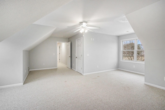 additional living space with vaulted ceiling, light carpet, and a textured ceiling