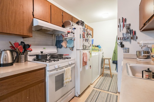 kitchen featuring separate washer and dryer, sink, decorative backsplash, and gas range gas stove