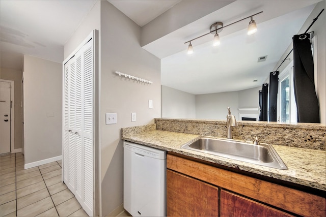 kitchen with sink, light stone countertops, dishwasher, and light tile patterned flooring