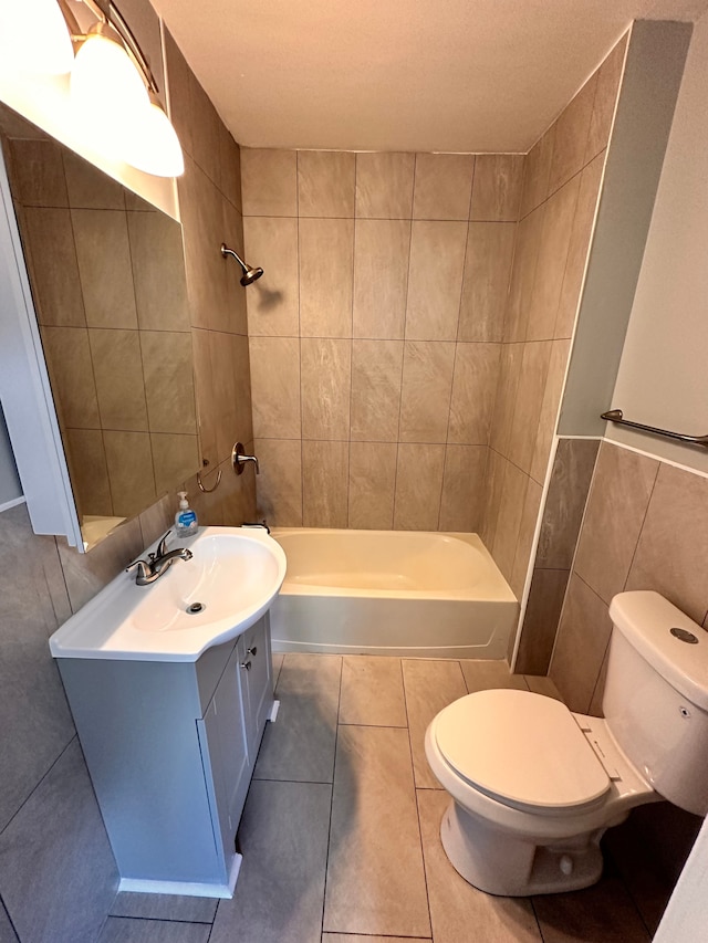 full bathroom with tiled shower / bath, tile walls, tile patterned flooring, vanity, and toilet