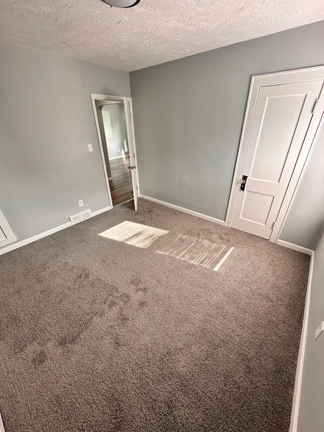 carpeted spare room featuring a textured ceiling