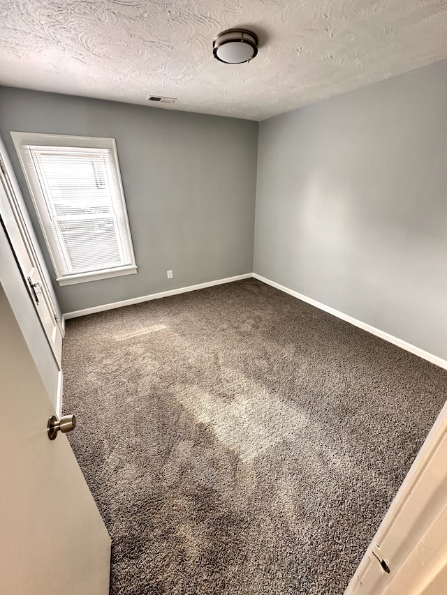 unfurnished room featuring carpet flooring and a textured ceiling