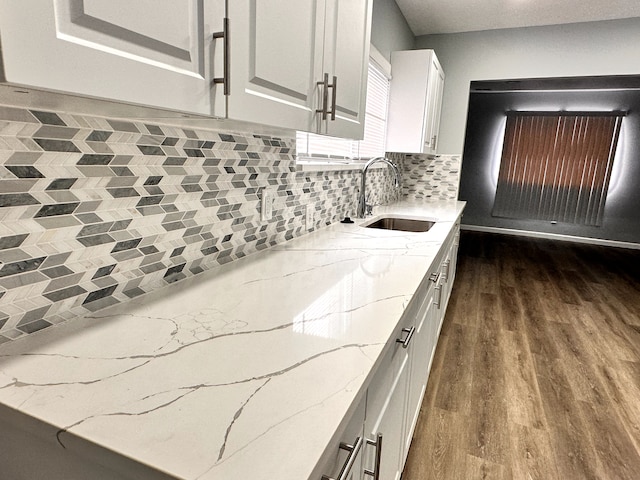 kitchen with sink, dark wood-type flooring, white cabinets, and light stone counters