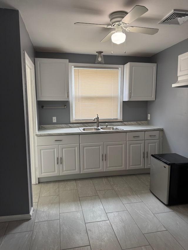 kitchen featuring white cabinetry, sink, stainless steel fridge, and ceiling fan