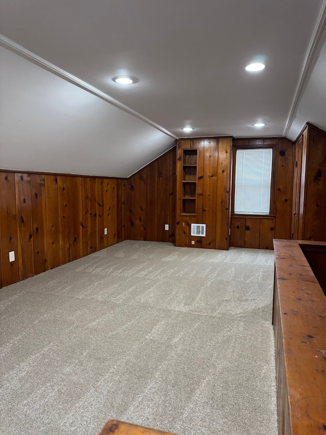 bonus room featuring light colored carpet, lofted ceiling, and wood walls