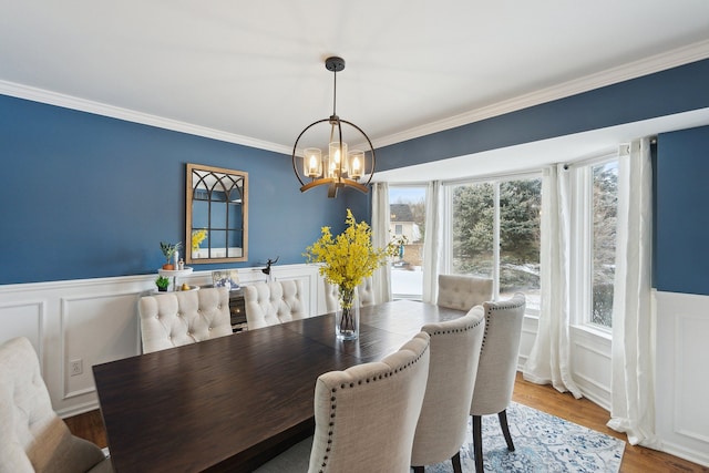 dining area with hardwood / wood-style flooring, ornamental molding, and a notable chandelier