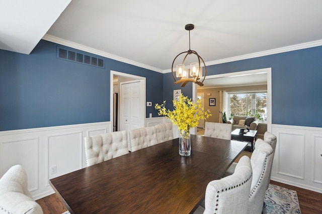 dining space featuring an inviting chandelier, ornamental molding, and dark hardwood / wood-style floors